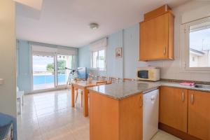 a kitchen with wooden cabinets and a table with a microwave at Apartamento Merida in Alcanar
