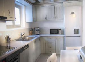 a kitchen with white cabinets and a sink and a microwave at House with private pool in Naousa