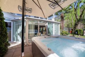 a hot tub with an umbrella in front of a house at Alpenhof Lodge Almrose in Saltusio