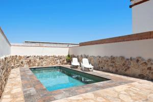 a swimming pool with two chairs on a patio at Casa Juana Zahora in Zahora