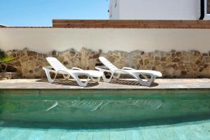 a group of white chairs sitting next to a pool at Casa Juana Zahora in Zahora