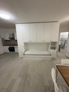 a kitchen with white cabinets and a bench in a room at Appartamenti Flora in Castelsardo