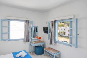a room with two windows and a table and a tv at Pico Bello Patmos 28 in Patmos