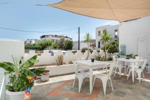 a patio with white tables and chairs and plants at Pico Bello Patmos 28 in Patmos