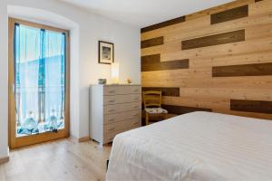 a bedroom with a white bed and a large window at Appartamento Lory in Cavedago