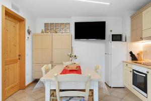 a kitchen with a table with chairs and a refrigerator at Appartamento Lory in Cavedago