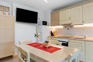 a kitchen with a table with chairs and a kitchen with white cabinets at Appartamento Lory in Cavedago +16 photos