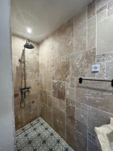 a bathroom with a shower with a tiled floor at Le Saint Marquan in Brantes