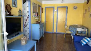 a living room with a tv and a blue table at Una casa sulla spiaggia in Es Grau