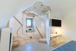 a bedroom with a bed and a tv on a wall at Trulli Tower in Putignano