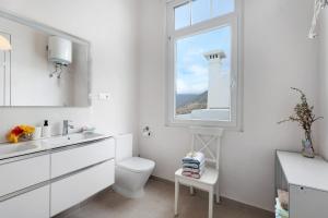 a white bathroom with a toilet and a window at Vista Alegre 22 A in El Paso +23 photos