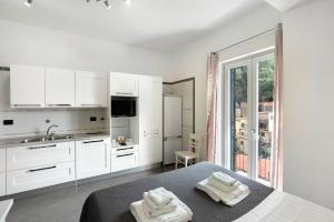 a white kitchen with white cabinets and towels on a bed at Ce Tour - Cetara Guest House in Cetara +30 photos