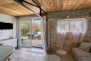 a living room with a couch and a sliding glass door at Chalet de Ferme - Spa - Gironde in Les Églisottes-et-Chalaures