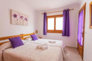 two beds in a room with purple curtains at Villa Loes in Menorca