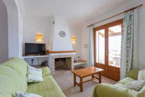 a living room with a green couch and a fireplace at Villa Loes in Menorca
