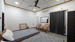 a room with two beds and chairs and a fan at KATHIR Guest House in Jaffna