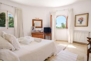 a white bedroom with a bed and two windows at Can Bernat in Can Furnet +24 photos