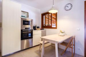 a kitchen with a table and a clock on the wall at Can Bernat in Can Furnet