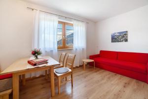 a living room with a red couch and a table at Fröhlichhof Wohnung Pergola in Lagundo