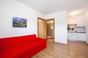 a living room with a red couch and a kitchen at Fröhlichhof Wohnung Pergola in Lagundo +16 photos