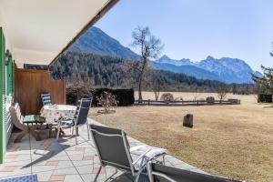 a patio with chairs and a table with mountains in the background at Alpenblick Tilly - Fewo Eibsee 1 in Krün