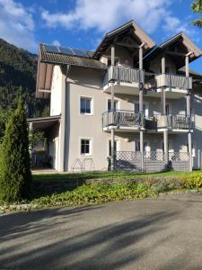 a white house with balconies and a street at Appartment Isabelle - Kamille in Lake Pressegg
