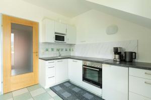 a kitchen with white cabinets and a black counter top at Appartment Isabelle - Kamille in Lake Pressegg