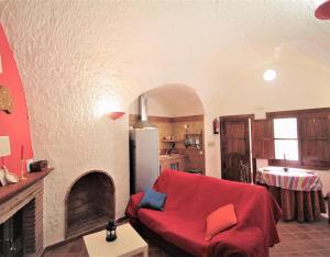 a living room with a red couch and a fireplace at Los Cerezos in Benalúa de Guadix
