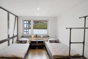 two beds in a room with a table and a window at De Lüttje Utkiek in Bühren