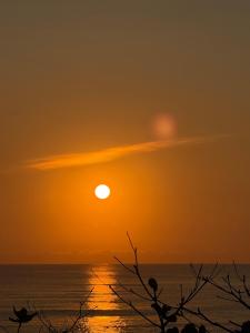 a sunset over the ocean with the sun in the sky at The Stoke Hideout Bagasbas Beach in Daet