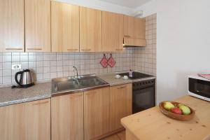 a kitchen with wooden cabinets and a bowl of fruit on a table at Ciasa Lino Rotic in Gardeccia - San Giovanni di Fassa