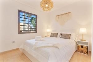 a white bedroom with a white bed and a window at Coco Canaria in Corralejo +26 photos