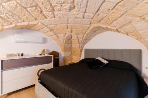 a bedroom with a bed and a stone wall at Casa Ninì in Galatone