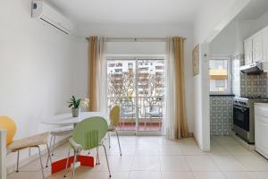 a kitchen with a table and chairs and a window at Casa De Pardal in Quarteira