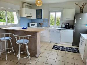 a kitchen with a counter and two bar stools at La Maison Du Rivage in Bretteville-sur-Ay +19 photos
