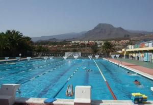 a large swimming pool with people in the water at Beach apartment in Los Cristianos in Los Cristianos
