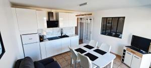 a kitchen with white cabinets and a table and chairs at Appartement T2 face à la mer in Saint-Vaast-la-Hougue