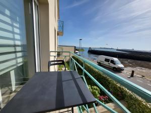 a balcony with a table and a white van on a street at Appartement T2 face à la mer in Saint-Vaast-la-Hougue +15 photos