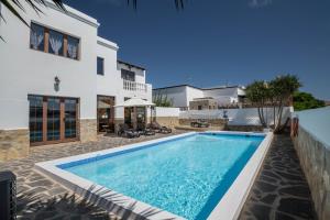 a villa with a swimming pool in front of a house at Villa María in Tinajo