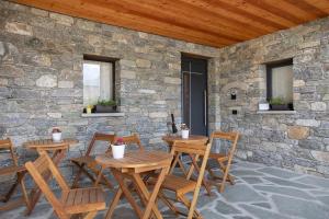 two tables and chairs on a patio with a stone wall at La Douce Pomme in Saint-Pierre
