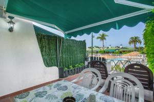 a table and chairs under a green umbrella on a balcony at Great Bungalow Maspalomas in Maspalomas