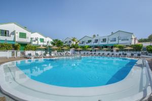 a large swimming pool at a resort with chairs and umbrellas at Great Bungalow Maspalomas in Maspalomas