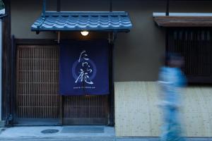 a man walking past a building with a sign on it at Tawara-an in Kyoto