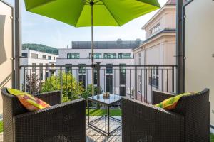 a balcony with chairs and a table with an umbrella at Schwarzwald Loft Baden-Baden in Baden-Baden