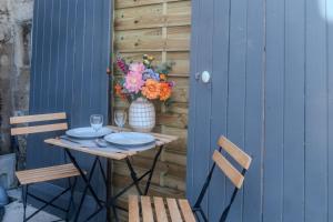 a table with two chairs and a vase of flowers at Le Lexa in Vindelle +18 photos