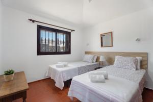 a room with two beds and a table and a window at Villa del Mar Palm Mar in Palm-Mar