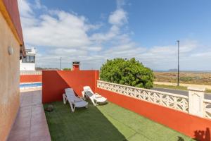 a balcony with two white chairs and an orange wall at Villa Atlantic Ocean Private Pool in Corralejo