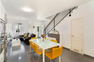 a living room with a white table and yellow chairs at Sunset Villa Meloneras in Maspalomas