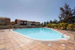 a large swimming pool on a tiled patio at Sunset Villa Meloneras in Maspalomas