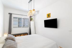 a white bedroom with a bed and a tv at Sunset Villa Meloneras in Maspalomas +17 photos